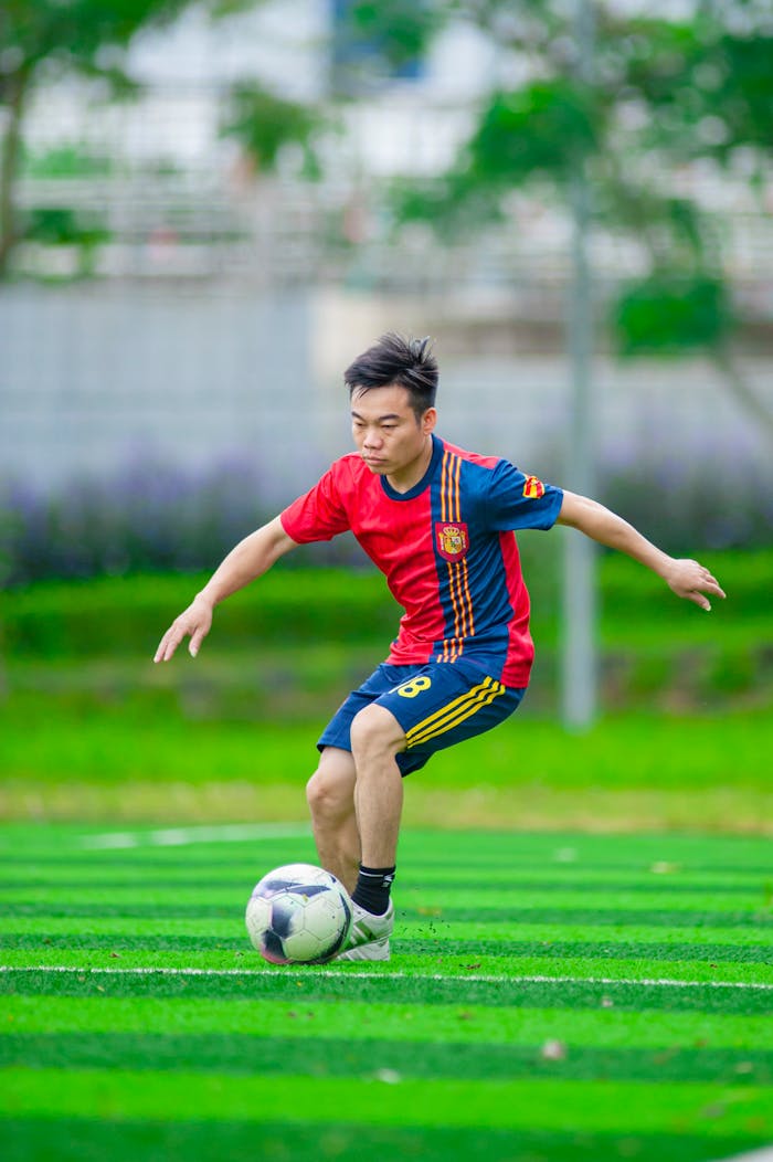 gallery-1 A young Asian male in a soccer jersey playing on a green field in Hanoi, Vietnam.