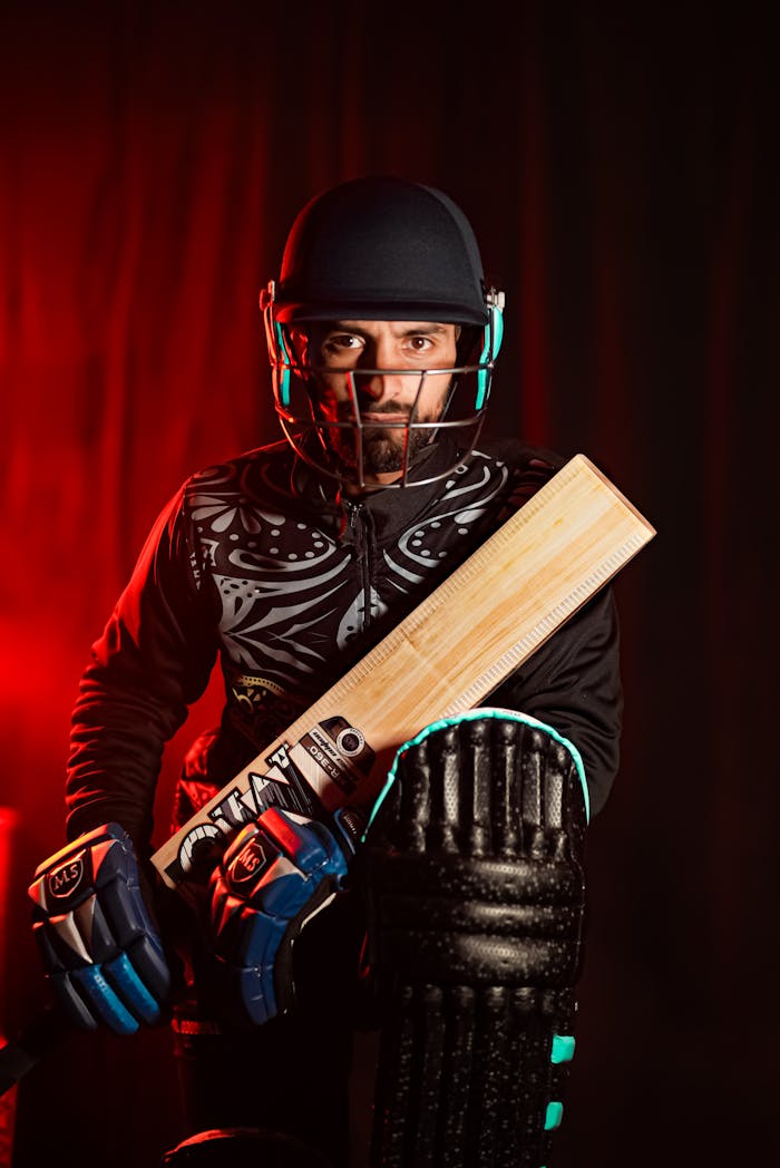 hero-img-02 Dynamic portrait of a cricketer in full gear, holding a bat ready for action.