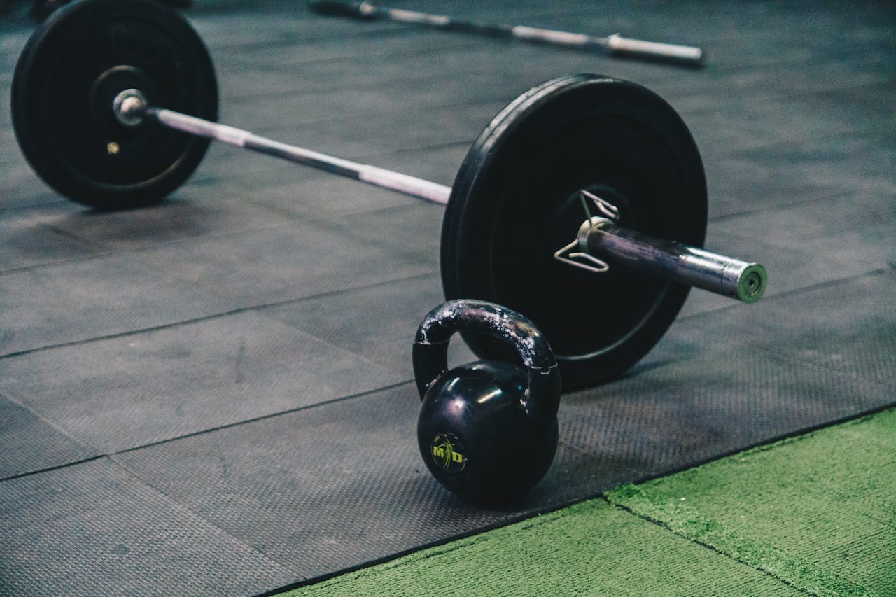 gallery-5 Barbell and kettlebell on gym floor, ideal for fitness and strength training themes.